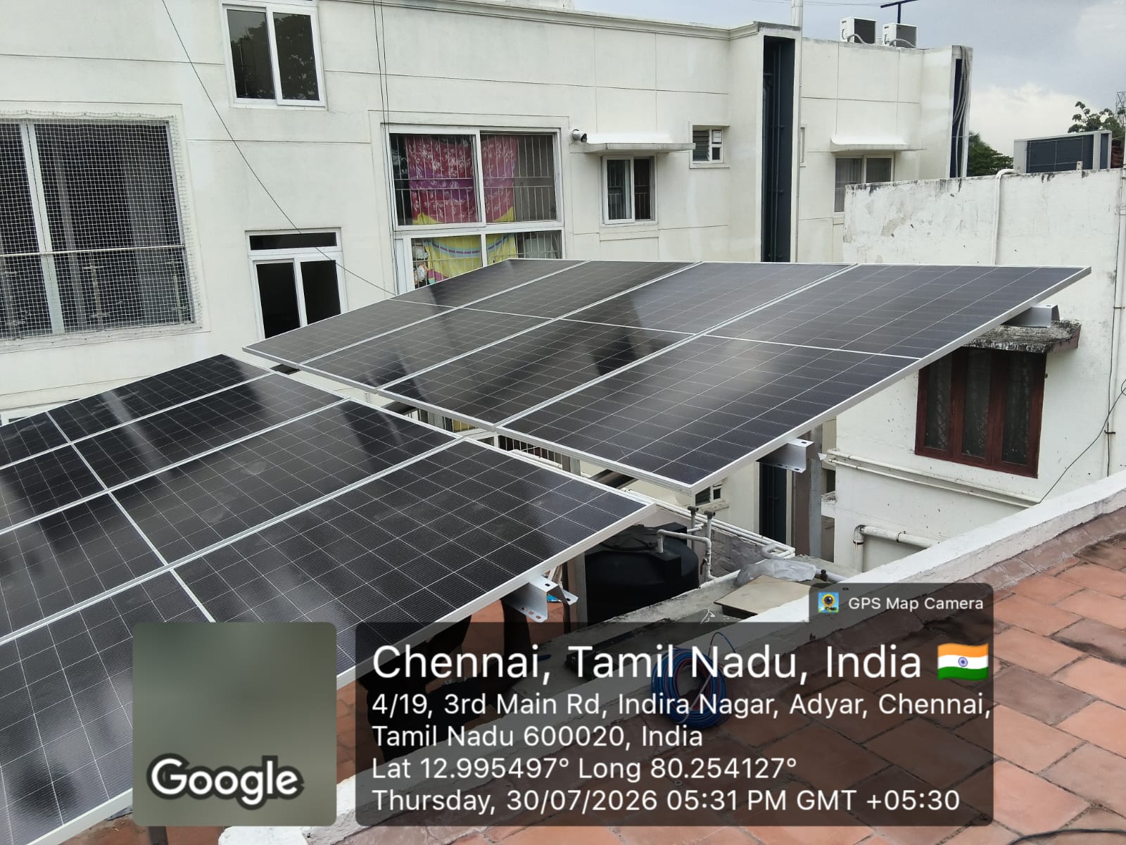 Solar panel installation at Adyar, Chennai — elevated terrace array over an urban rooftop.